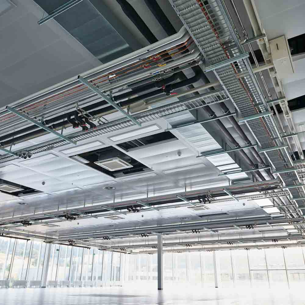 Installation de câblage électrique au plafond avec structures métalliques, illustrant la technologie du bâtiment chez Flückiger.