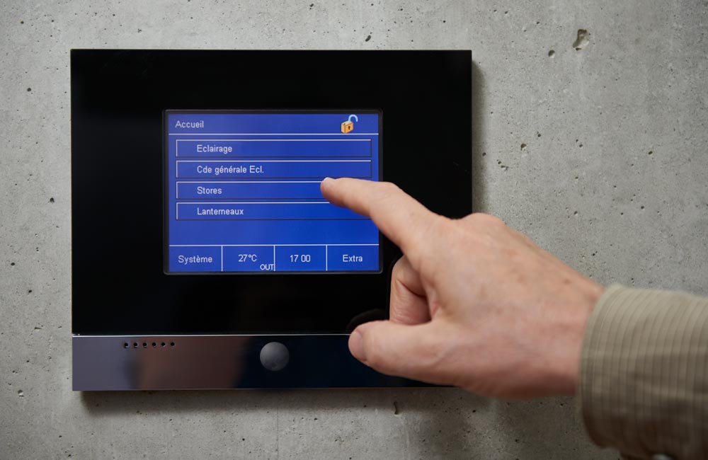 Panneau de commande tactile gérant éclairage, stores et autres fonctions dans un bâtiment, reflétant les technologies modernes intégrées par Flückiger.