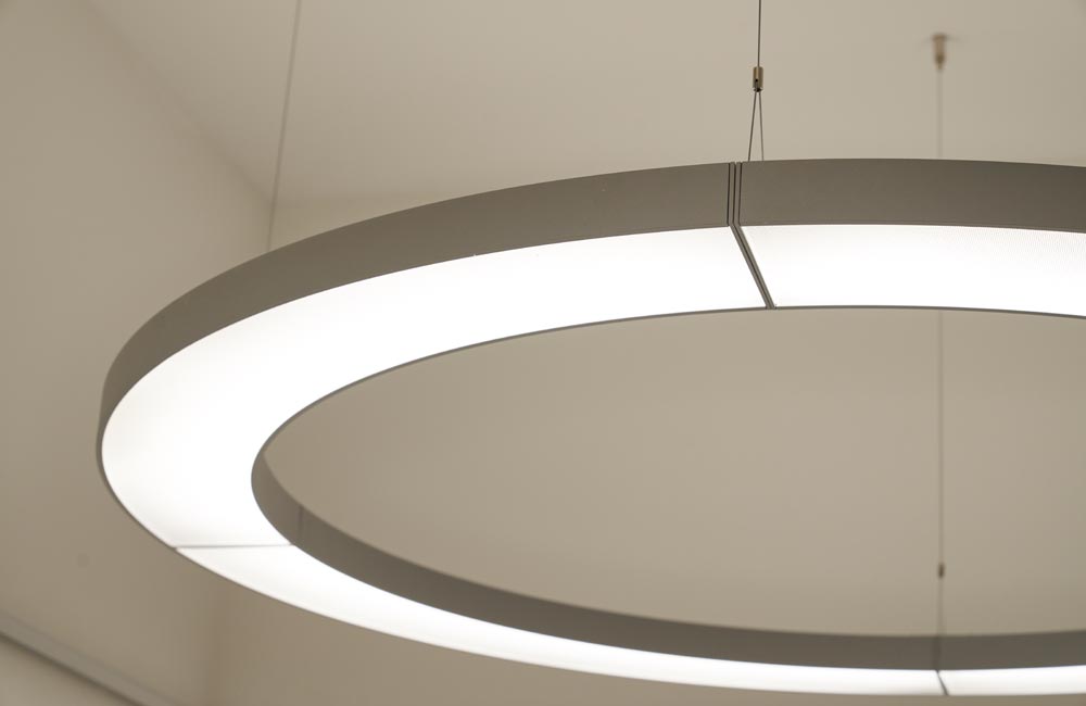 Lampe suspendue éclairant un bureau moderne, illustrant l'utilisation de solutions d'éclairage décoratif et fonctionnel par Flückiger.