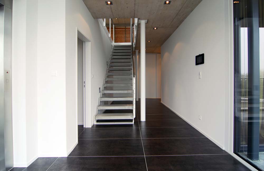 Cage d'escalier avec commandes murales dans un corridor, reflétant les solutions pratiques et esthétiques de Flückiger pour le contrôle domestique.