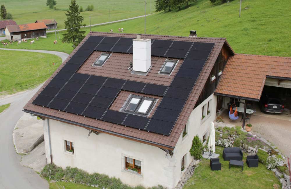 Grande maison rurale dotée de panneaux solaires sur le toit, ressemblant à une exploitation agricole, illustrant l'intégration de solutions d'énergie renouvelable par Flückiger dans des environnements ruraux.