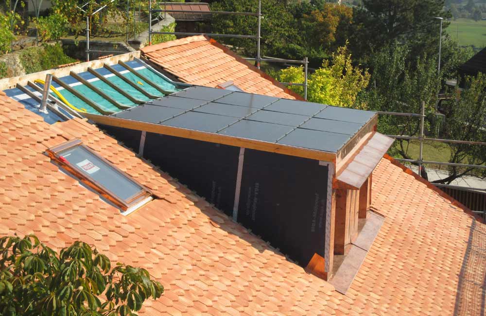 Toit avec avancée équipé de panneaux solaires installés à l'horizontal, en cours d'installation, démontrant la capacité de Flückiger à fournir des solutions photovoltaïques personnalisées pour toutes configurations de bâtiment.